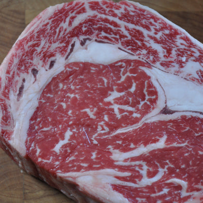 A close-up of a raw marbled steak on a wooden cutting board.